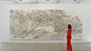 Woman in a red suit looking at a wall sized black and white abstract print