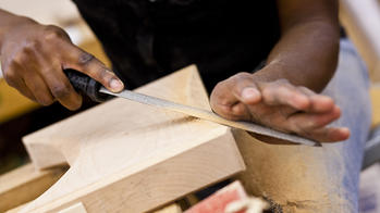 A Furniture Design student hand-filing a block of wood