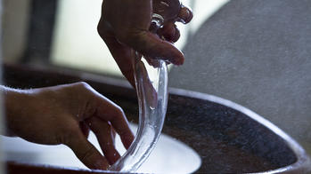 a Glass student shapes work in progress by hand