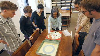 students around a table looking at a piece of art