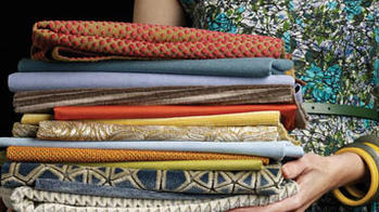 a person holding a stack of woven textiles 