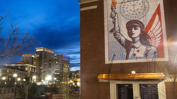 An artwork by Shepard Fairey titled RI Angel of Hope and Strength projected onto the RISD Auditorium exterior at night in downtown Providence