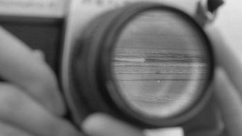 a black-and-white photo by RISD alum John Shen of hands focusing a camera lens