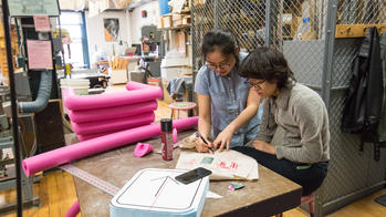 Two Industrial Design students prototyping with pink pool noodles.