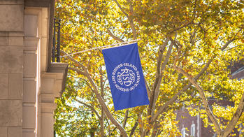 Blue RISD flag against yellow autumn leaves