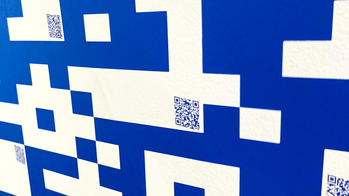 three small blue QR codes situated in the white spaces of a larger QR code