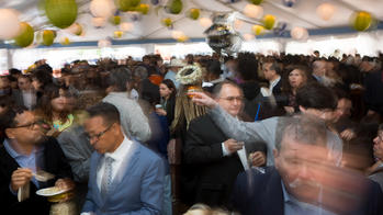 Crowd of people celebrating in a tent with paper lanterns.