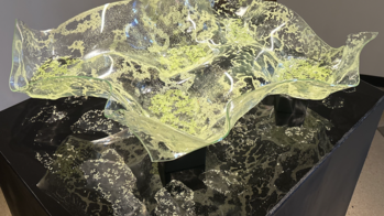 a pale green glass piece reminiscent of a topography map