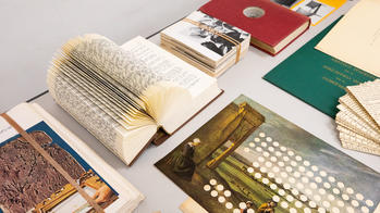 several books and other print objects spread out on a display table