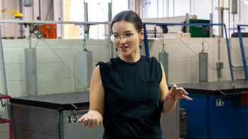 Abby Sunde in a black sleeveless shirt wearing glasses speaking in a studio