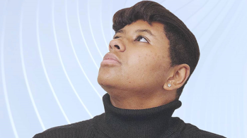 Appellonia Williams in a black turtleneck looking up to the left in front of a blue and white swirled background