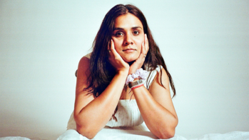 Priyanka Kumar leaning forward with head in hands against a light grey background