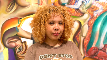 Shiyeon Ku in a brown t shirt with the words don't stop in front of a multicolored mural