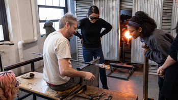 Students and faculty in the hot shop blowing glass