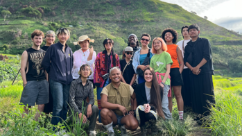 Students in a group facing the camera standing in a green mountainous area