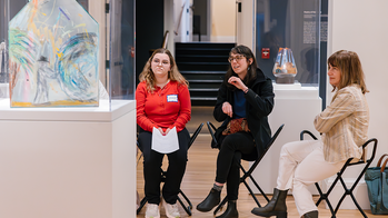 Museum visitors sitting in front of a work of art discussing the piece