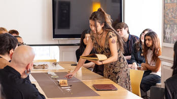 A group of people are gathered around a table and interacting with displayed materials.