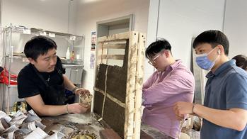 three students working on a large brick structure