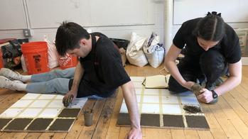 two students working with clay matter samples on the ground