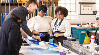 three people making art around a table