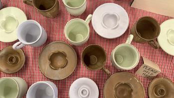 green brown and off-white mugs on a red and white tablecloth