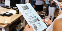 Hands holding a flyer about a Lettepress shop open house, as part of  DESIGN WEEK RI 