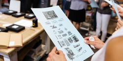 Hands holding a flyer about a Lettepress shop open house, as part of DESIGN WEEK RI