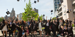 large group of gowned students throw their caps in the air
