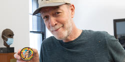 Bill Adler holds up a small tin of candy with a Devil Girl comic on the lid