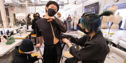 student models a garment held together with safety pins