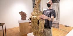 grad student Jacob Sussman sets sculpture on a pedestal
