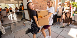 Students hold a box in front of the dorms on move in day