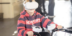 a kid wearing a VR headset rides a stationary bicycle