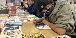 Students sit around a table full of zines at Queer Archive Works and draw