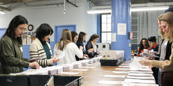 Members of the Alumni Club of Boston assemble copies of a Braille book at National Braille Press