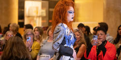 A model walks down the runway in drag and a red with in a garment made by Disco Amber