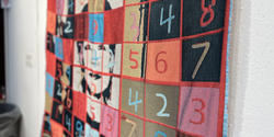 A quilt by Xiao Guo featuring a sudoku grid overtop an image of her mother's face in bright colors