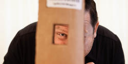 an instructor peers through a hole in a piece of cardboard