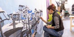 a student working on a huge painting in studio