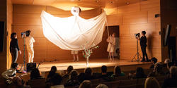 A massive white dove spreads its wings across the Metcalf Auditorium stage