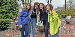 four happy POD grads pose for a photo in front of Woods-Gerry House