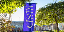 the sun illuminating a RISD flag on a summer day