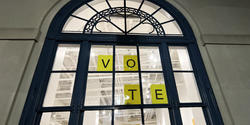 simple yellow signs that spell out the word Vote in window of the Design Center