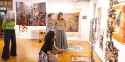 Mary Anne Friel and other faculty members consider a room of final student textiles