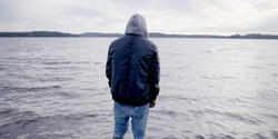 a fully dressed man walking out into the sea