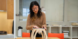 student presents a small plywood-and-acrylic stool