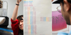 tech Nat Luo holds up a sample of digitally printed fabric in the Mimaki print room