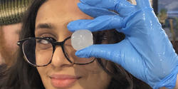 student playfully holds a biomaterial sample up to her eye