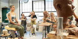 students surround the model as they finish their clay portraits