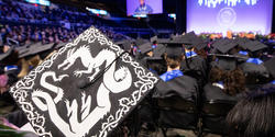 mortaboard decorated with image of dragon and RISD Commencement behind